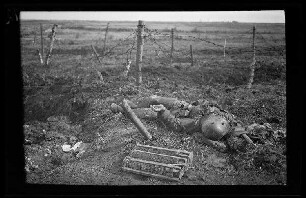 Nicht identifizierbare Gegend in Nordfrankreich oder Belgien: gefallener Soldat auf dem Feld neben einem Stacheldrahtverhau ("Gefallene")