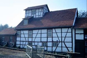ehemalige Wassermühle an der B 7; Mühlengebäude mit Dachaufsatz; Mühlsteine an der Wand