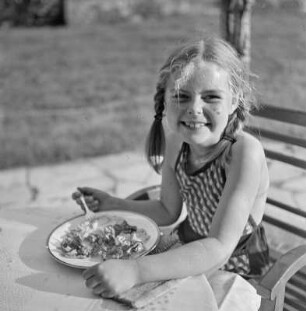 Mädchen isst auf einer Terrasse