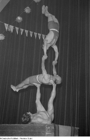 Drei Männer auf einer Bühne formen eine menschliche Pyramide auf einem Lampionfest des Kreisfriedensrats