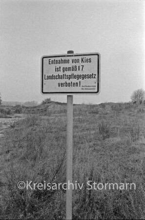 Kieskuhle: vorn Verbotsschild zur Kiesentnahme: dahinter Gestrüpp: hinten links Sandflächen: dahinter Büsche