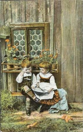 [Mädchen und Junge sitzen vor Holzhaus]