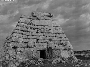 Naveta des Tudons : Person vor der Ruine einer prähistorischen Grablege bei Ciutadella