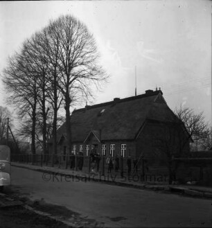 Volksschule mit Reetdach: Oetjendorfer Landstraße: davor Schulhof mit Zaun und Baumreihe: spielende Schulkinder: vorn Straße: links Maicomobil