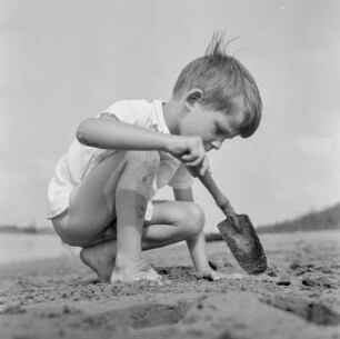 Junge schaufelt im Sand am Strand