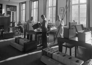 Drei Mitarbeiter des Bildarchivs Foto Marburg im Lesesaal des Kunstgeschichtlichen Seminars der Marburger Philipps-Universität bei den Vorbereitungen für die Fotokampagne im besetzten Frankreich 1940/41