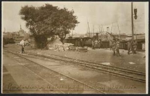 Arbeiter am Güterbahnhof in Istanbul, am Bosporus-Ufer. Im Vordergrund Schienen, im Hintergrund Schiffe und der Blick auf einen nördlich gelegenen Stadtteil und Umriss einer Moschee. Beginn des Baus der Bagdadbahn in der Türkei