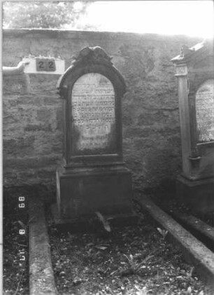 Grabstein 22 (Index: 100105740) Material: Sandstein und Marmor Zustand: Schrifttafel zerbrochen und repariert Maße HxBxT: 158x62x31 cm Beschreibung: Stele, profilierter Sockel, Rundbogenabschluß mit Aufsatz, eingesetzte Schrifttafel Steinmetz: Klein: Grabstein 22