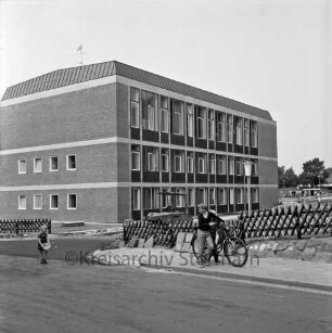 Rathaus und Bürgerhaus Glinde [später Marcellin-Verbe-Haus]: Neubau vor Fertigstellung: Blick vom Oher Weg: vorn links Kind: rechts Junge mit Fahrrad: dahinter Jägerzaun und Bagger