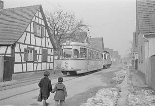 Stadtteil Daxlanden. Großraum-Straßenbahnwagen zwischen Fachwerkhäusern.