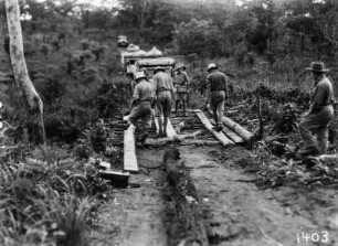 Vorbereitung der Überfahrt : Teilnehmer der Expedition bereiten eine Brücke für die Überfahrt mit den Fahrzeugen vor, welche im Hintergrund stehen.