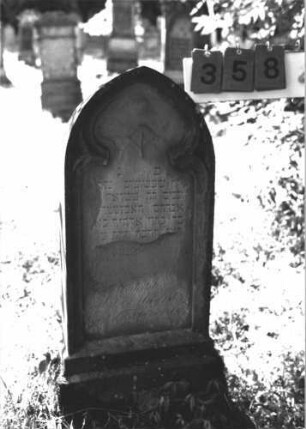 Grabstein 358 (Index: 100106740) Material: Sandstein Zustand: stark verwittert, in Platten abgesprungen, weitgehender Textverlust Maße HxBxT: 99x38x12 cm Beschreibung: Stele mit Spitzbogenabschluß, Schriftfeld eingetieft in Maßwerkform, getreppter Sockel Symbolik: floral Besonderheit: Kindergrab: Grabstein 358