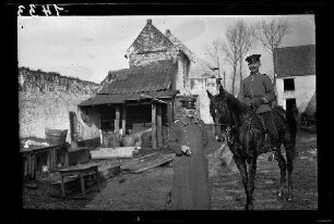 Nicht identifizierbare Ortschaft in Nordfrankreich: 2 Offiziere mit Schirmmütze, einer davon zu Pferd, im morastigen Hof eines landwirtschaftlichen Anwesens