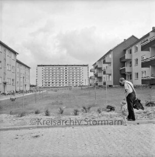 Klosterbergen: Bogenstraße: rechts und links dreigeschossige Wohnblocks: in der Mitte Grünanlage mit Wäschestangen: vorn rechts Mann mit Kind und Plastikauto: hinten Mitte achtgeschossiges Punkthaus nach Fertigstellung
