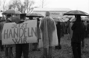 Sasbach: Kundgebung gegen Bleiwerk Marckolsheim und Atomkraftwerk Wyhl; Protestwehrversammlung im Regen mit Plakaten