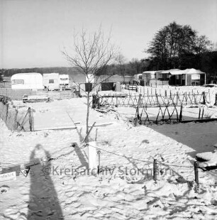 Großensee: Südufer: Campingplatz mit winterfesten Wohnwagen und Vorzelten: vorn Wiese mit leeren Stellflächen: hinten rechts Baum: im Hintergrund Wald: Winter