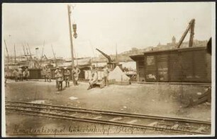 Arbeiter in Uniform an Güterbahnhof in Istanbul, Bosporus-Ufer. Im Vordergrund Schienen, im Hintergrund Schiffe und der Blick auf den gegenüberliegenden Stadtteil Galata. Beginn des Baus der Bagdadbahn in der Türkei