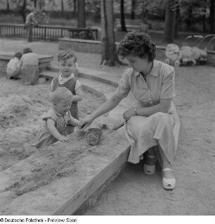 Mutter mit Kindern im Sandkasten auf einem Spielplatz im im Clara-Zetkin-Park