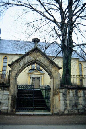 steinernes Portal zum Kirchhof, dahinter Kirche