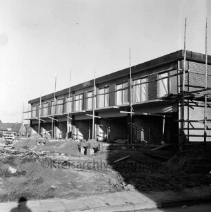 Wikingerweg: Wohnungsbau: Reihenhäuser im Rohbau mit Gerüsten: vorn Baumaterial: hinten links Einfamilienhäuser: rechts Schatten