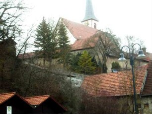 Ansicht von Südwesten mit Kirchenburg in Spornlage über dem Ort - Kirchhofmauer mit Wehrgang und innen angebauten Gaden nach Restauration