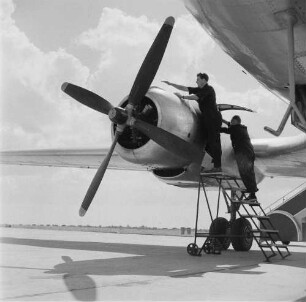 Leipzig-Mockau. Flughafen, Vorfeld. Zwei Techniker bei Wartungsarbeiten an einem Flugzeugmotor