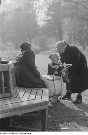 Zwei alte Frauen und ein Kleinkind sowie ein Kinderwagen im Park