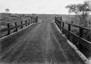 Brücke : Eine Brücke, über die eine Straße führt. Im Hintergrund eine Graslandschaft.