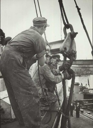 Hamburger Hafen. Arbeiter sichern auf einem Schiff die Last mit Hilfe von Trossen