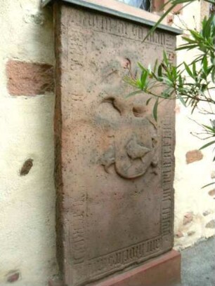 Ansicht von Süden - Langhaus-Grabstein (teils verwittert) mit Wappenkartusche und Umschrift