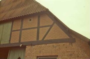 Hohenfelde 7: Bauernhaus: Giebelseite Wirtschaftstrakt: Teilansicht: Giebel mit Fachwerk, Luke, Eulenloch: oben Eternitdach
