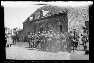 Bei Paschendaele (=Passendale, Belgien), Beccelacre (=Beselare, Belgien) oder in der Gegend von Tenbrielen (=Ten Brielen, Belgien): bewaffneter Soldatentrupp mit Feldmützen "vor einem Estaminet: 'de Blokstraat-Estaminet'" (Distanzaufnahme)