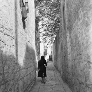 Verschleierte Frau in einer schmalen Gasse einer Altstadt