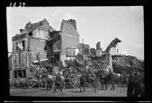 Péronne (?) (Dep. Somme, Frankreich): Reiter und Fuhrwerke auf einer gepflasterten Ortsstraße vor einer hohen Gebäuderuine (Rückansicht)