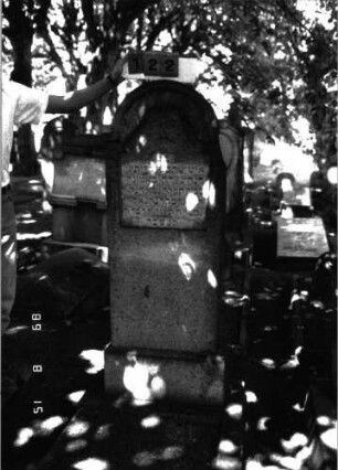Grabstein 122 (Index: 100105342) Material: Granit Zustand: verwittert mit Textverlust Maße HxBxT: 167x56x21 cm Beschreibung: Stele, Sockel, eingezogener Rundbogenabschluß, rechteckiges Schriftfeld erhaben Symbolik: Blattwerk über Schriftfeld: Grabstein 122