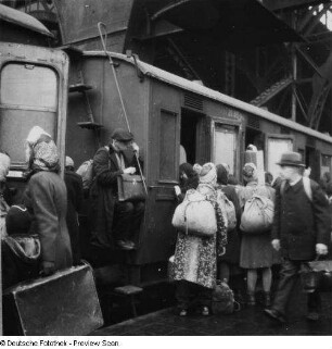 Leipzig. Hauptbahnhof. Überfüllter Personenzug ("Hamsterzug") mit einsteigenden Reisenden, ein Passagier sitzt auf einer Wagonleiter