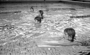 DSV-Schule. Kinder beim Erlernen des Schwimmens mit Hilfe eines speziellen Brettes