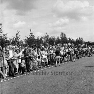 "Old Reinfelder Jungs e.V.": 25-jähriges Jubiläum: Musikfest: Stadion am Bischofsteicher Weg: Zuschauer hinter Geländer an der Aschenbahn, 18. August 1974
