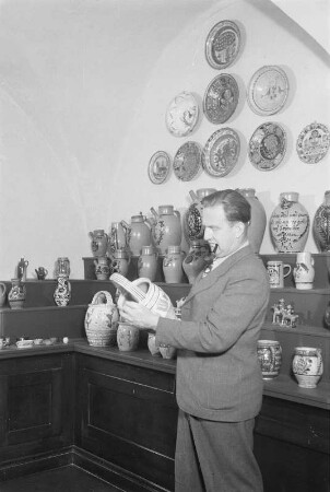 Dresden, Köpckestraße 1: Museum für Sächsische Volkskunst mit Puppentheatersammlung (1927-1949 Oskar-Seyffert-Museum), Ausstellung Erdgeschoßhalle nach Rücktransport der ab 1942 in Schloss Weesenstein eingelagerten Bestände. Direktor Reinhold Langner vor Nische mit bäuerlicher Keramik