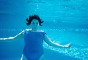 Mädchen in blauem Badeanzug bläst unter Wasser die Backen auf (Altersgruppe 14-17)