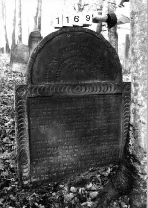Grabstein 1169 (Index: 99903004) Material: Sandstein Zustand: etwas eingesunken Maße HxBxT: 119x99x8 cm Besonderheit: kulturhistorisch wertvoll / künstl.-formale Gründe: Grabstein 1169