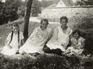 Zwei Frauen und zwei Mädchen auf einer Decke im Freien sitzend