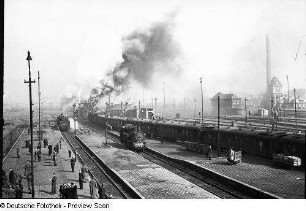 Deutschland. Bahnhof. Blick über Bahnsteige und Gleise mit Dampflokomotiven und Personenzug