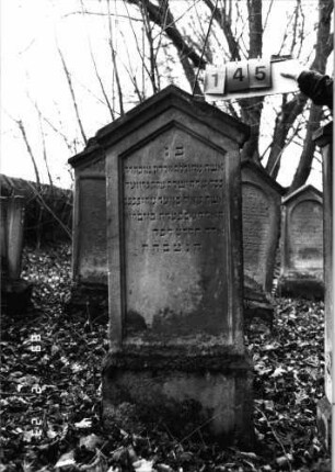 Grabstein 145 (Index: 99751962) Material: Sandstein Zustand: gut Maße HxBxT: 142x52x19 cm Beschreibung: Stele, Sockel, giebelartiger Abschluß mit Verdachung, Schriftfeld eingetieft: Grabstein 145
