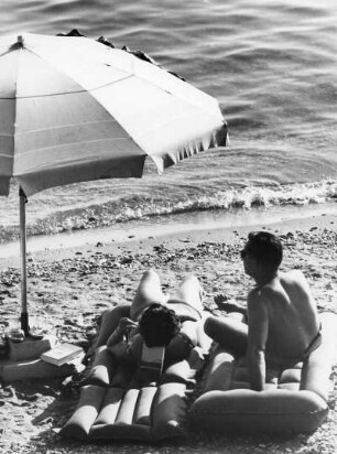 Sommerurlaub an der See. Ein Paar liegt auf Luftmatratzen am Strand