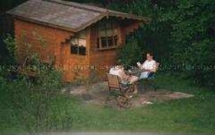 Mann und Frau sitzen vor ihrem Gartenhäuschen (Altersgruppe 18-21)