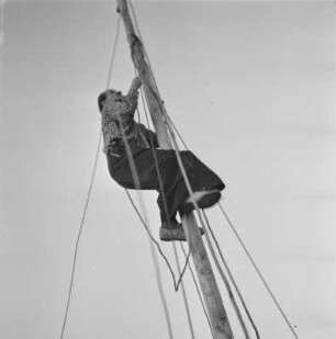 Mann befestigt Seile am Mast eines Segelboots
