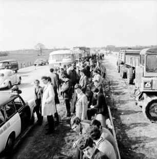 A 1: bei Stapelfeld: Verkehrsunfall: in Autobahnbaustelle: Auffahrunfall von zwei Bussen und einem Lastwagen: hinten Unfall-Busse und Unfall-Lkw hintereinander: davor auf Grünstreifen Busfahrgäste sitzend und stehend, Geländer:vorne links Polizeiwagen, links Leitkegel, vorbeifahrende Autos: rechts Baustelle, Baufahrzeuge: Aufnahme unscharf, 30. April 1969