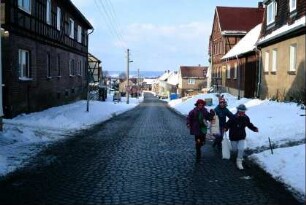 Dorfstraße mit Häusern, Kinder in Faschingskostümen