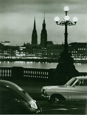 Hamburg-Altstadt bei Nacht. Blick von der Lombardsbrücke über die Binnenalster Richtung Hamburger Rathaus. Im Hintergrund der Turm des Mahnmals St. Nikolai